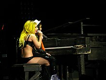 Gaga assise sur un tabouret de piano alors qu'une jeune fille est posée sur ses genoux.