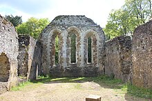 grey stone walls leading to an end wall with three tall window openings