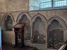 The piscina (left of wooden lectern) and sedilia in St. Mary's church, Buriton, Hampshire
