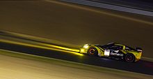 A yellow and black grand touring car in night time conditions