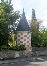 Photographie en couleurs d'une tourelle surmontée d'une poivrière et entourée d'un mur d'enceinte.