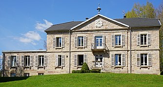 Un manoir de style Napoléon III avec un fronton, un balcon, une terrasse à l'étage et de nombreuses cheminées.