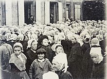 foule de femmes en coiffe et fichu, au premier plan, un enfant coiffé d'un béret.