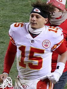Patrick Mahomes jogging in a Kansas City Chiefs uniform while carrying his helmet.