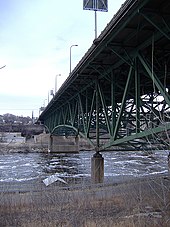 Puente pintado de verde visto desde el banco de Mississippi