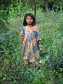 una bambina india in mezzo alle erbe alte, vestita di azzurro