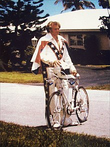 A man in a caped uniform standing next to a bicycle