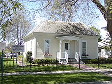 A small house sits by a sign reading "Historic site, Mamie Doud Eisenhower Birthplace, Museum and Library"