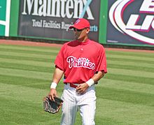 A man in white pants and a red baseball jersey and cap