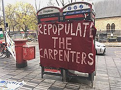 A red banner with white-lettered slogan tied across two phone boxes