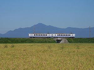 米山をバックにほくほく線を走るHK100形 （2014年9月 くびき駅-犀潟駅間）