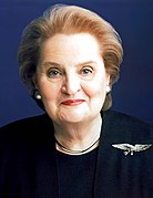 Photographie de Madeleine K. Albright en 1997, représentante du Secrétariat des États-Unis, une femme de couleur de peau blanche, cheveux bruns et portant un costume entièrement noir, avec une broche représentant son pays.