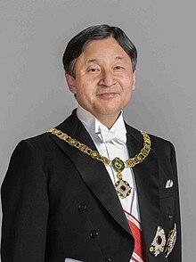 Wearing white tie and tails with sash and medals