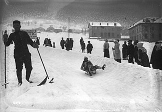 Dans un décor enneigé, une femme évolue sur une luge devant des spectateurs curieux.