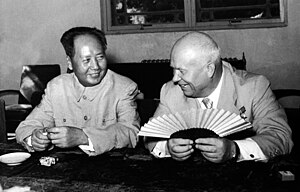 Nikita Kruschev dan Mao Zedong yang lebih muda duduk dan tersenyum