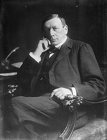 seated portrait photo of a dark-haired clean-shaven man aged 64