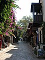 A street in Kaş with traditional houses and a Lycian tomb in the background