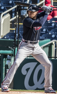 A baseball player in a navy jersey and gray pants