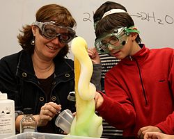 A teacher and a student doing the elephant's toothpaste experiment in a classroom setting.