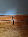 Rigid metal spring doorstop in baseboard molding