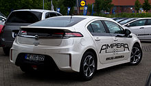 Rear 3/4 view of a Navajo-White colored automobile with large, black labelling that says AMPERA