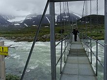 Photo d'un pont métallique dans le parc, il enjambe un cours d'eau dont le débit est élevé.