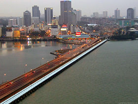 La chaussée Johor-Singapour vue de Woodlands Checkpoint à Singapour, en face se trouve Johor Bahru, la capitale de l'État de Johore en Malaisie. À droite de la chaussée en blanc : les canalisations qui permettent à Singapour d'être approvisionnée d'eau douce depuis la Malaisie.