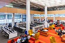 university library with bright lights and students working in groups at tables