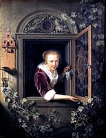 A girl in a window with a bunch of grapes