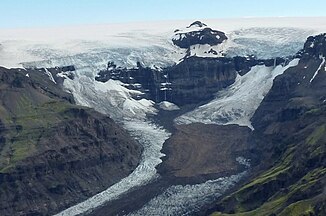 Blick von den Kristínartindar-Gipfeln auf den Morsárfoss in den Felsen in der Bildmitte; auf den Felsen liegt die Eiskappe des Vatnajökull, unterhalb von ihnen beginnt der Morsárjökull.