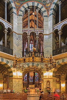 The interior of a tall church with two levels of columns covered by arches