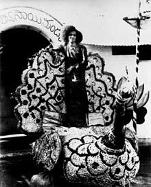 Sathya Sai Baba standing on a float in a parade.