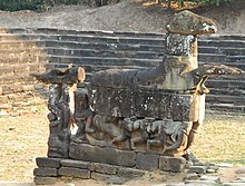 Grande statue en blocs de pierre représentant un cheval avec les membres étendus en avant, des hommes accrochés à ses flancs.