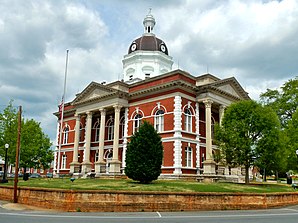 Meriwether County Courthouse (2013). Das Courthouse entstand 1903/04 im Stil der Colonial-Revival-Architektur und ersetzte einen Vorgängerbau von 1832. Ausführender Architekt war J. W. Golucke, auf den viele Gerichts- und Verwaltungsgebäude in Georgia und Alabama zurückgehen. Im Mai 1973 wurde das Meriwether County Courthouse als zweites Objekt im County in das NRHP eingetragen.[1]