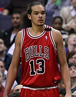 A basketball player, wearing a red jersey with the word "BULLS" and the number 13 on the front, is standing on a basketball court.