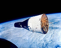 A black and white spacecraft, with the Earth below it.