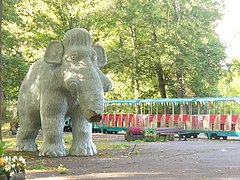 Photographie d'une statue de mammouth devant un petit train.