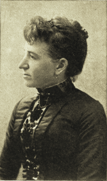 B&W portrait photo of a woman with her hair in an up-do, wearing a dark blouse.