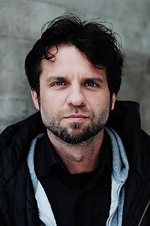 Dark-haired, bearded, casually dressed man