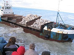 Le samedi 9 décembre 2006, la toute première barge chargée de roches s'approche du pied de falaise. Les habitants n'avaient jamais vu un tel bateau à cet endroit de la plage et ils sont des centaines à assister aux opérations.