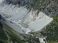 Un léger cours d'eau sortant d'un glacier recouvert de pierres.