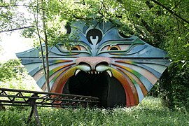 Photographie de l'entrée d'un tunnel sur le circuit des montagnes russes, en forme d'animal fantastique.