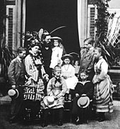 Photographie en noir et blanc d'un groupe de sept enfants et adolescents avec leurs parents.