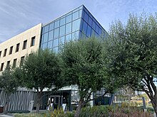 A modern looking building with mostly glass walls surrounded by newly installed, high-end landscaping.