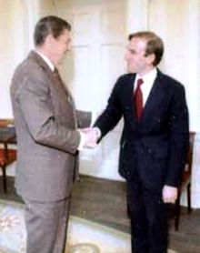 Two men in suits shaking hands in the Oval Office