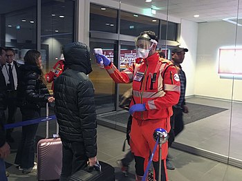 A Protezione Civile (Civil Protection) volunteer measures the temperatures of people before they enter Guglielmo Marconi Airport in Italy