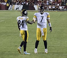 Deux joueurs de football américain se serrant la main sur un terrain.