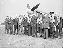 Photographie en noir et blanc d'un groupe d'hommes posant devant un avion.