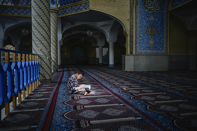 Мальчик читает книгу в мечети города Сенендедж, Курдистан, Иран