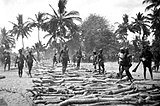 Om een grafsteen te kunnen slepen wordt de weg versterkt met verplaatsbare boomstammen waarover een slede wordt gerold, Oost-Sumba, 1931